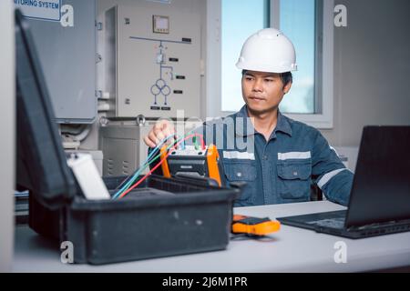 Der Techniker lädt die Daten aus dem Tool zur Leistungsüberprüfung des Solarpanels herunter, um sie auf einem Computer zu analysieren, damit die Stromerzeugung mit vollem capa betrieben werden kann Stockfoto