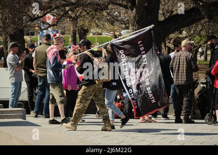 Ottawa, Ontario, Kanada - 30. April 2022: Ein Protestler trägt eine schwarze Gadsden-Flagge mit der Aufschrift „tritt nicht auf mich ein“ und fügte „Freiheit oder Tod“-Slogans hinzu. Stockfoto