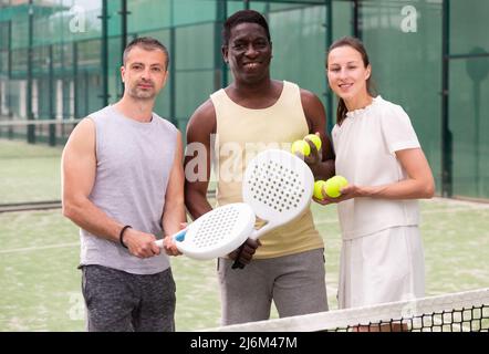 Drei Paddle-Tennisspieler posieren auf dem Platz Stockfoto