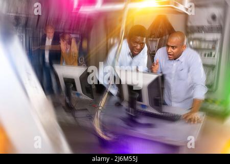 Männer in Angst auf der Suche nach einer Lösung auf dem Computer im Quest-Raum Stockfoto