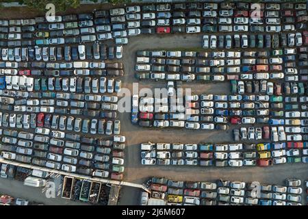 Luftaufnahme des großen Parkplatzes von Schrottplatz mit Reihen von weggeworfenen gebrochenen Autos. Recycling von Altfahrzeugen Stockfoto