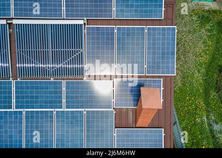 Gebäudedach mit Reihen von blauen Photovoltaik-Paneelen und Vakuum-Luft-Solarkollektoren für die Warmwasserbereitung und die Produktion von sauberem ökologischem Strom Stockfoto