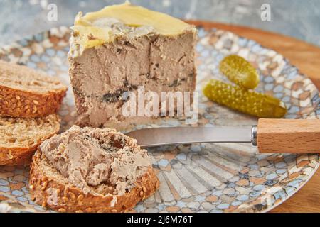 Hühnerleber-Pastete mit Trüffeln mit Brotmesser und Gurken Stockfoto