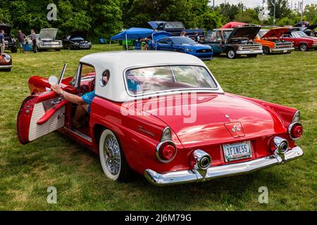 Ein Mann öffnet bei einer Show in Fort Wayne, Indiana, USA, die Tür zu seinem stilvollen roten Ford Thunderbird Sportwagen aus dem Jahr 1955. Stockfoto