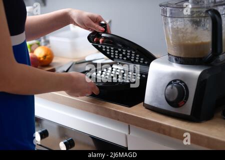 Frau, die in der Küche ein belgisches Waffeleisen zubereitete Stockfoto