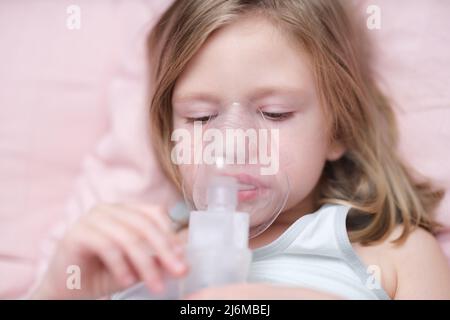 Kleines trauriges Mädchen, das Inhalation hat, um Husten zu lockern Stockfoto