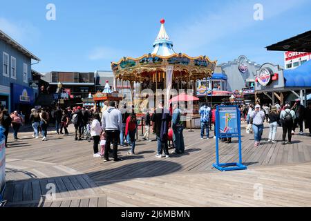 Karussell, Geschäfte und Besucher am Pier 39 in San Francisco, Kalifornien, USA an einem sonnigen Tag; Tourismus und Touristen in der Bay Area. Stockfoto