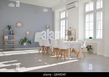 Leeres Büro mit Konferenztisch, Stühlen, Whiteboard, Regalen und Innenpflanzen Stockfoto