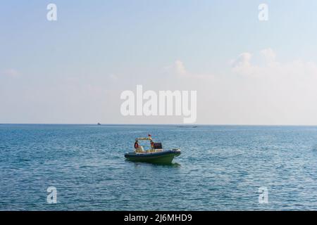 Ein kleiner offener weißer Fischer steht an einem sonnigen Tag auf dem Wasser Stockfoto