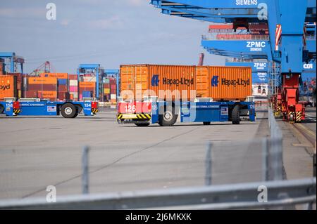 27. April 2022, Hamburg: Auf dem Gelände des HHLA Container Terminal Altenwerder (CTA) werden Container mit der Bezeichnung 'Hapag-Lloyd' von einem digital gesteuerten, fahrerlosen Fahrzeug verladen. Foto: Jonas Walzberg/dpa Stockfoto