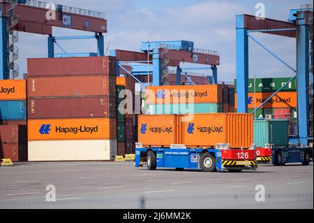 27. April 2022, Hamburg: Auf dem Gelände des HHLA Container Terminal Altenwerder (CTA) werden Container mit der Bezeichnung 'Hapag-Lloyd' von einem digital gesteuerten, fahrerlosen Fahrzeug verladen. Foto: Jonas Walzberg/dpa Stockfoto