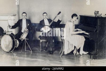 Archiviertes Sepia-Foto der „Bonzo Trio“-Jazzband, 1927, England. Jack Jim und die Pianistin Puppe Mather in einem flapperförmigen Kleid Stockfoto
