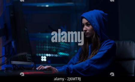Junge Frau Hacker durch Computer im dunklen Raum in der Nacht, Cyberwar-Konzept. Stockfoto