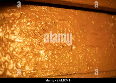 Gelbe Wand im Licht der Sonne. Große Farbschicht. Textur der unebenen Oberfläche. Stockfoto