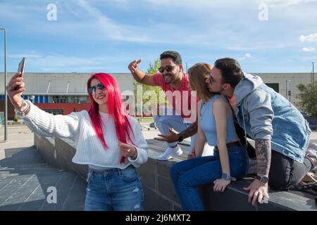 Eine Gruppe von vier jungen Freunden, die mit dem Mobiltelefon ein Foto machen Stockfoto