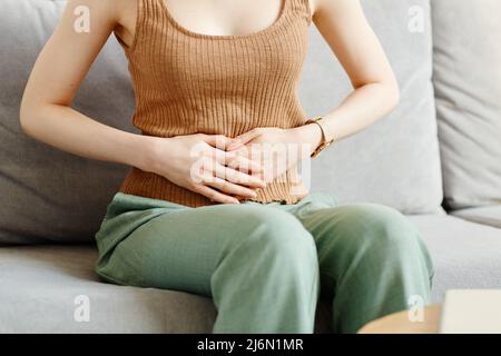 Minimale abgeschnittene Aufnahme einer jungen Frau, die an Krämpfen leidet und die Hände am Bauch hält, Platz kopieren Stockfoto