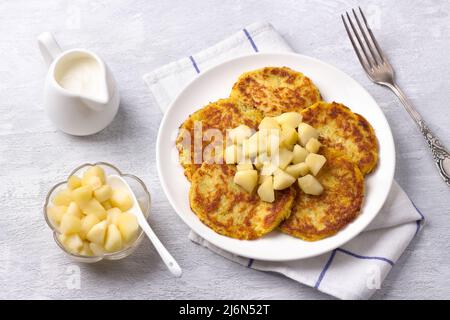 Traditionelle Latkes-Krapfen mit saurer Creme- und Apfelsauce auf hellgrauem texturiertem Hintergrund, Draufsicht Stockfoto