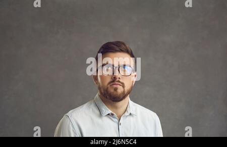 Ernsthafter Mann in einer Brille, der etwas Verdächtiges anschaut und darüber nachdenkt, was man dagegen tun soll Stockfoto