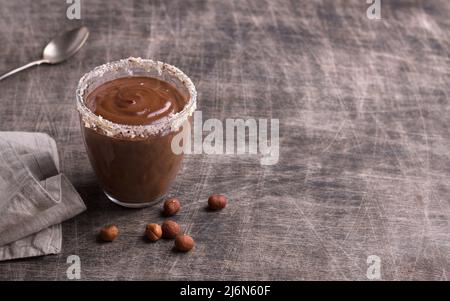 Schokoladenmousse mit Creme und Haselnüssen in Gläsern auf altem dunklen Holztisch, Freiraum, selektiver Fokus Stockfoto