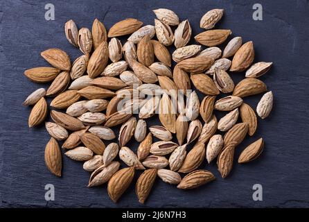 Verschiedene Nüsse auf schwarzem Schiefergrund. Mandeln, Walnüsse, Haselnüsse, Pistazien. Draufsicht Stockfoto