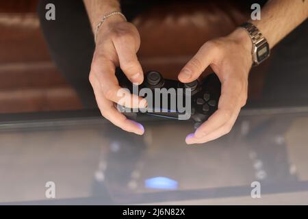 Spielkonzept. Teil Körper Mann mit Joystick spielen Spiel auf der Konsole. Polster mit männlichen Händen. Hochwertige Fotos. Stockfoto