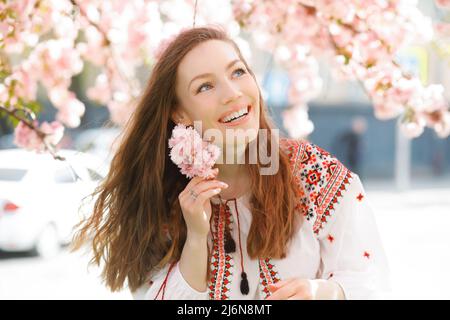 Nahaufnahme romantisches Porträt einer jungen schönen Frau im Blütenpark mit rosa Blumen Stockfoto