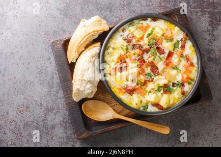 Hausgemachte Gemüsekartoffelsuppe mit geräuchertem Speck in der Schüssel auf dem Holztablett. Horizontale Draufsicht von oben Stockfoto