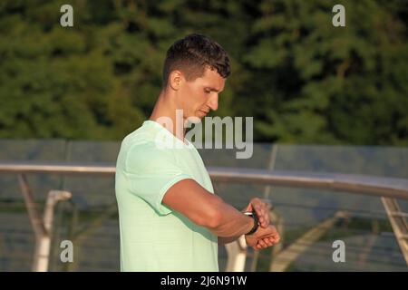 Analyse seines Ergebnisses. Der Mann überprüft die Zeit nach dem Training auf der Uhr. Belastungsdauer. Sportliches Timing Stockfoto