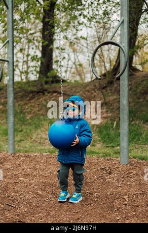 Ein kleiner Junge hält einen Boxsack in einem Park auf der Straße Stockfoto