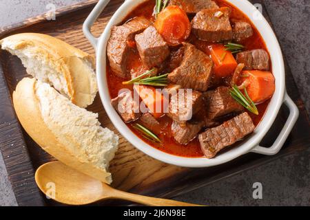 Französisches Rindfleisch-Eintopf in Rotwein, auch als taube de boeuf provenzalische Nahaufnahme bekannt, in der Holzschale auf dem Tisch. Horizontale Draufsicht von oben Stockfoto