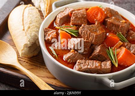 Französisches Rindfleisch-Eintopf in Rotwein, auch als taube de boeuf provenzalische Nahaufnahme bekannt, in der Holzschale auf dem Tisch. Horizontal Stockfoto