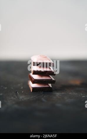 Selektive Konzentration auf vier Schokoladenscheiben auf dunklem Hintergrund. Stockfoto