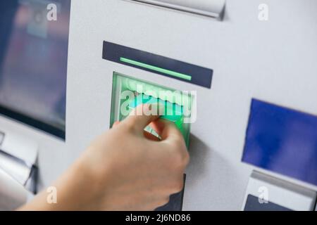 Frau, die eine Kreditkarte in den Geldautomaten einsteckt, um Geld zu überweisen oder abzuheben. Konzept der Finanzkunden- und Bankdienstleistungen Stockfoto
