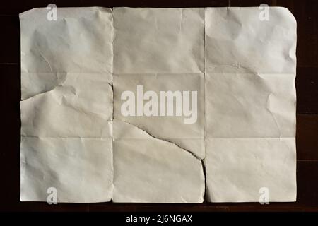 Altes, weißes gefaltetes Papier auf dunklem Holzhintergrund Stockfoto