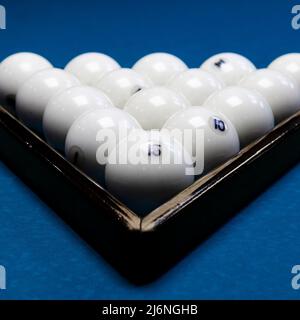 Weiße Billardkugeln für Billard, ein Dreieck auf dem Tisch. Weiße Billardkugeln für Billard auf blauem Hintergrund Stockfoto