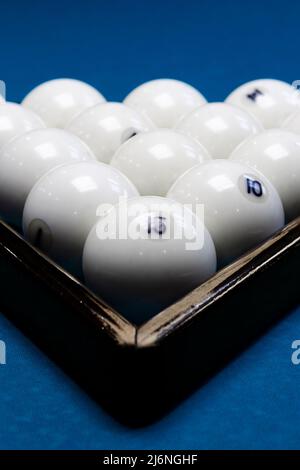 Weiße Billardkugeln für Billard, ein Dreieck auf dem Tisch. Weiße Billardkugeln für Billard auf blauem Hintergrund Stockfoto