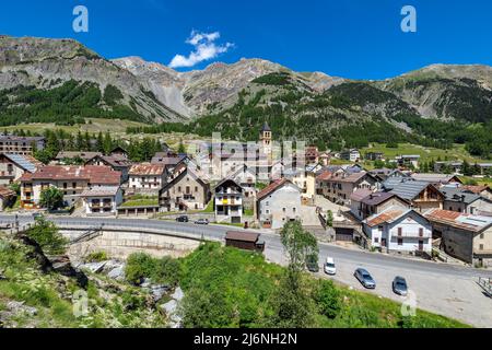 Blick von oben auf die kleine alpine Stadt Bersezio am Fuße der Berge unter blauem Himmel im Piemont, Norditalien. Stockfoto