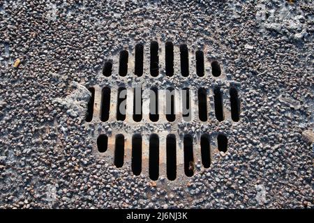 Runder Schachtdeckel mit Kies nach dem Winter Stockfoto
