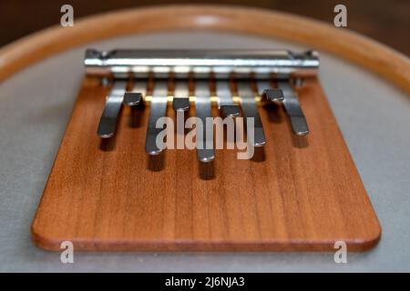 Neun Metalltasten eines hölzernen Musikinstruments Kalimba oder Sansula aus der Nähe. Stockfoto