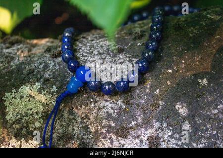 Nahaufnahme von blauen mala-Perlen auf Stein. Buddhistische Gebetsperlen für die Japa-Meditation Stockfoto