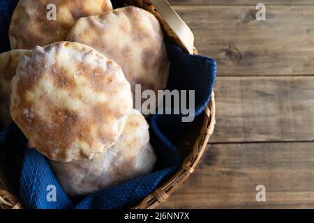 Korb mit hausgemachtem Pita-Brot auf alten Holzbrettern. Kopierbereich, Draufsicht. Stockfoto