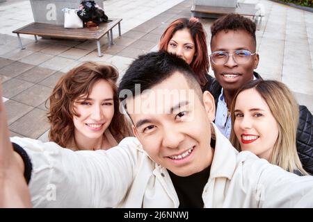 Von oben asiatischer Mann lächelnd und Selfie mit multirassischen Freunden am Wochenende auf der Straße Stockfoto