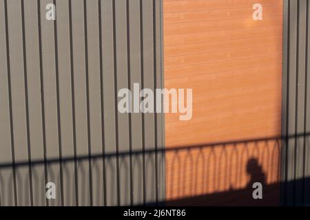 Schatten an der Wand. Schwarze Schatten an einem hellen Tag. Ungewisse Schießerei in der Stadt. Stockfoto