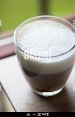 Heißer Kaffee mit Milchschaum in einem transparenten Glas. Ansicht von oben. Stockfoto