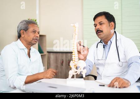 Arzt erklärt älteren Patienten Rückenschmerzen mit Wirbelsäulenmodell im Krankenhaus - Konzept der Beratung und Beratung Stockfoto