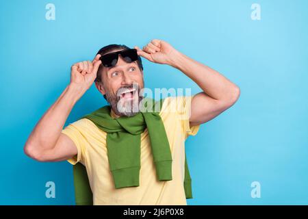 Portrait von beeindruckt positive Mann Hände berühren Gläser aussehen interessiert leeren Raum isoliert auf blauem Hintergrund Stockfoto