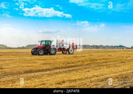 Traktor mit Feldspritze fährt über das Feld Stockfoto