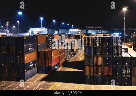 25. April 2022 - Birzebbuga, Malta: Schiffscontainer mit gewerblicher Fracht, die nachts in einem Umschlagzentrum gestapelt sind Stockfoto