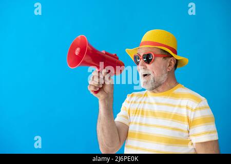 Glücklicher älterer Mann, bereit zu reisen. Person, die über Lautsprecher schreit. Sommerurlaub und Urlaubskonzept Stockfoto