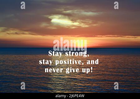 Motivierende und inspirierende Zitate – Bleib stark, bleibe positiv und gib nie auf. Auf dem Hintergrund des Sonnenuntergangs Licht über dem Ozean. Stockfoto